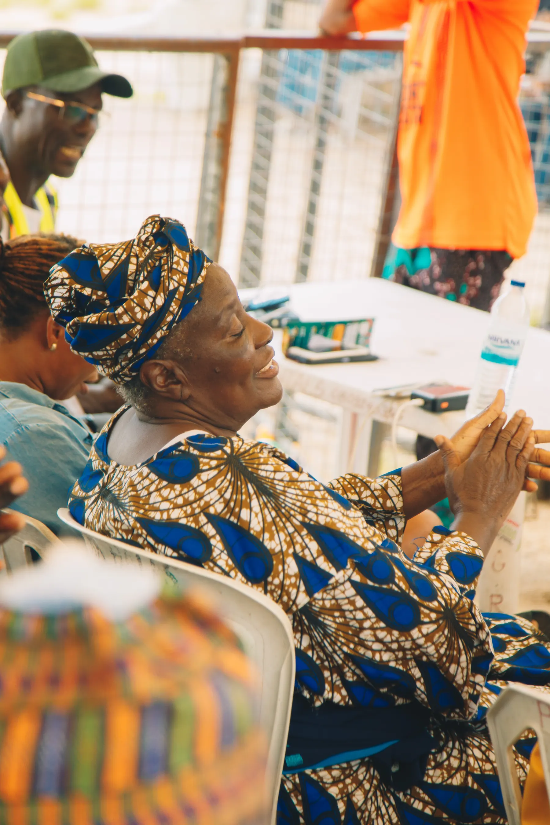 An elderly woman smiling with her hands clasped at a Smiley Caring Foundation relief event in Lagos.