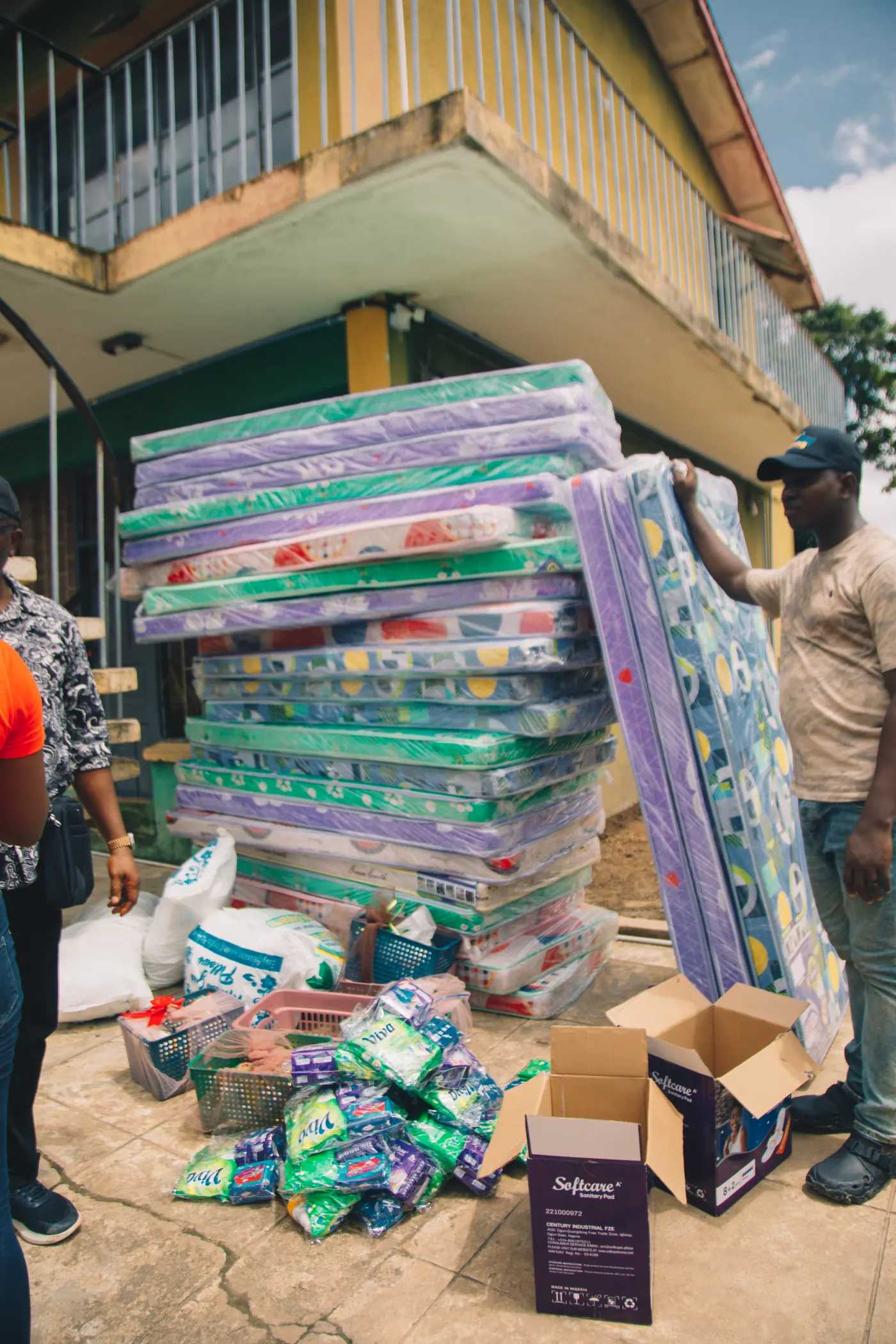 Stacks of mattresses being carried in for delivery by the Smiley Caring Foundation.