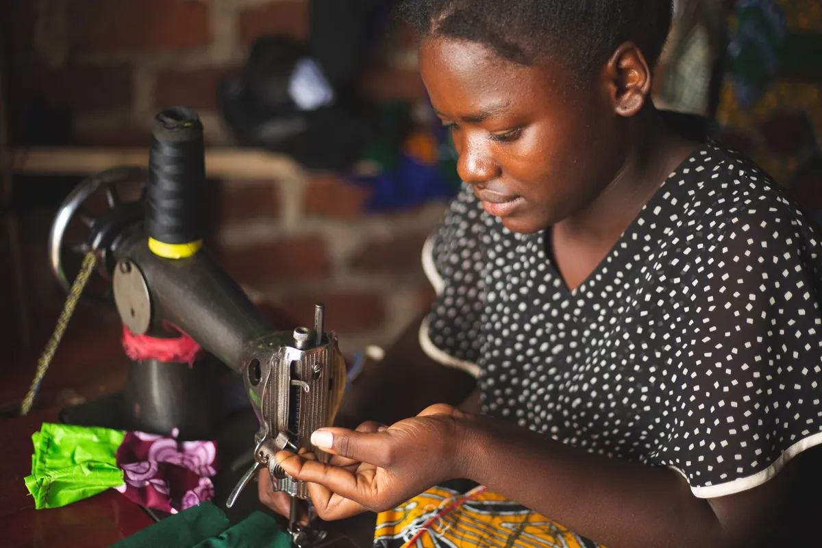 A seamstress concentrating at her sewing machine in a workshop.